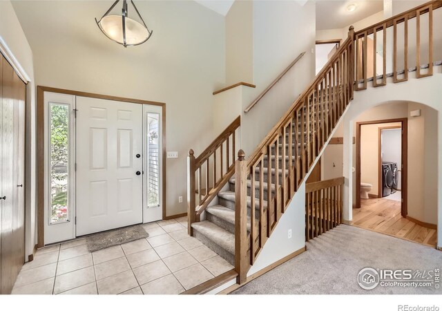 379 E 41st Ct, Loveland, CO 80538 - entryway featuring separate washer and dryer, a high ceiling, arched walkways, stairs, and baseboards