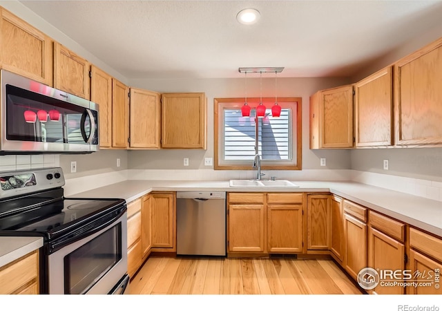379 E 41st Ct, Loveland, CO 80538 - kitchen with appliances with stainless steel finishes, a sink, light wood-type flooring, light countertops, and hanging light fixtures