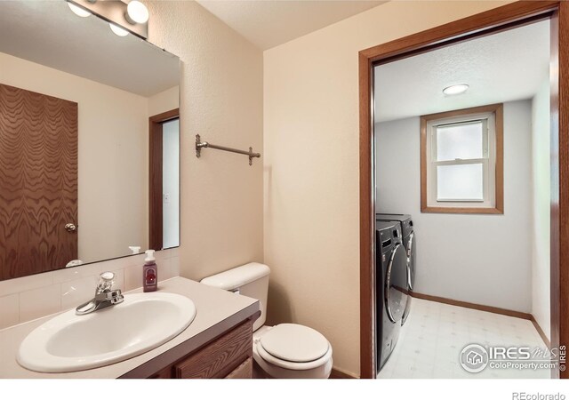 379 E 41st Ct, Loveland, CO 80538 - half bath with washing machine and clothes dryer, tile patterned floors, toilet, and vanity