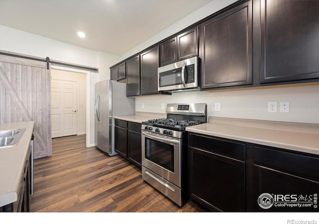 6793 Hayfield St, Wellington, CO 80549 - kitchen with appliances with stainless steel finishes, light countertops, dark wood-style flooring, recessed lighting, and a barn door