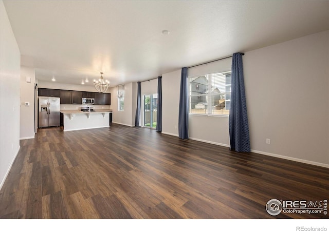 6793 Hayfield St, Wellington, CO 80549 - unfurnished living room with a chandelier, dark wood-style flooring, and baseboards