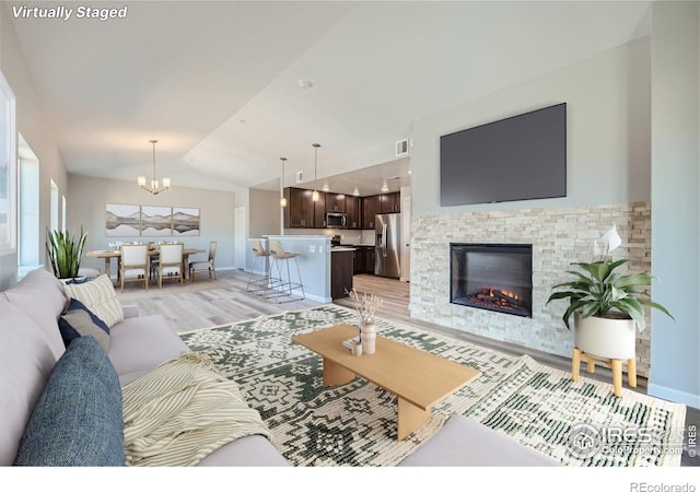 2435 Calais Dr Unit G, Longmont, CO 80504 - living room featuring light wood finished floors, a glass covered fireplace, lofted ceiling, baseboards, and a chandelier