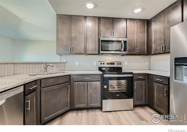 2435 Calais Dr Unit G, Longmont, CO 80504 - kitchen with stainless steel appliances, light wood finished floors, dark brown cabinetry, a sink, and tasteful backsplash