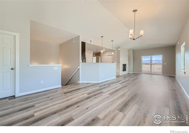 2435 Calais Dr Unit G, Longmont, CO 80504 - unfurnished living room with light wood-type flooring, vaulted ceiling, a chandelier, and baseboards
