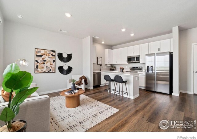 259 Molinar St, Johnstown, CO 80534 - living area featuring dark wood-style floors, baseboards, and recessed lighting
