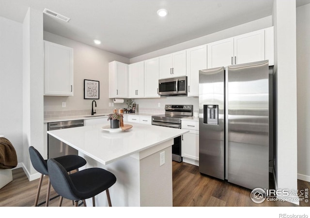 259 Molinar St, Johnstown, CO 80534 - kitchen featuring appliances with stainless steel finishes, a kitchen bar, dark wood-type flooring, recessed lighting, and white cabinets