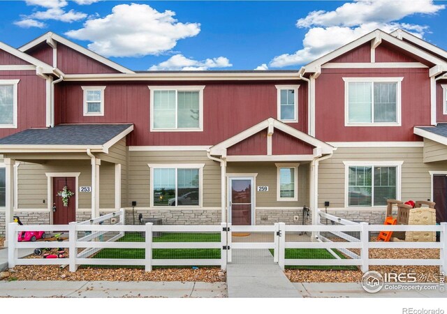 259 Molinar St, Johnstown, CO 80534 - townhome / multi-family property featuring stone siding, covered porch, a fenced front yard, and a gate