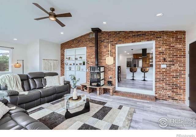 128 Carpenter Rd, Fort Collins, CO 80525 - living area featuring a wood stove, a ceiling fan, lofted ceiling, wood finished floors, and brick wall