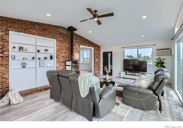 128 Carpenter Rd, Fort Collins, CO 80525 - living room featuring brick wall, a wood stove, a ceiling fan, light wood-style floors, and healthy amount of natural light