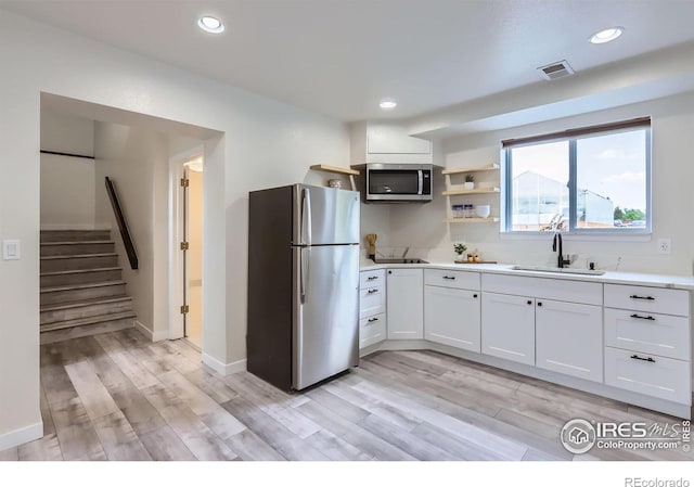128 Carpenter Rd, Fort Collins, CO 80525 - kitchen featuring appliances with stainless steel finishes, a sink, light countertops, light wood-type flooring, and white cabinetry