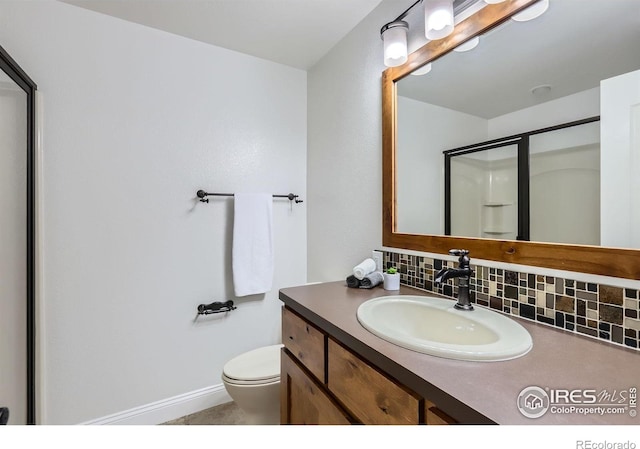 128 Carpenter Rd, Fort Collins, CO 80525 - bathroom featuring tasteful backsplash, vanity, toilet, a shower with door, and baseboards