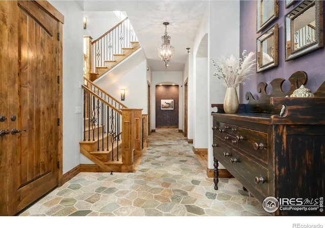 5709 Old Legacy Dr, Fort Collins, CO 80528 - entrance foyer featuring arched walkways, stone floors, stairway, and a chandelier