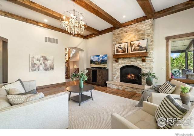 5709 Old Legacy Dr, Fort Collins, CO 80528 - living area with arched walkways, wood finished floors, a stone fireplace, beamed ceiling, and a chandelier