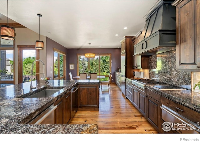 5709 Old Legacy Dr, Fort Collins, CO 80528 - kitchen featuring light wood-style floors, custom exhaust hood, stainless steel appliances, tasteful backsplash, and hanging light fixtures