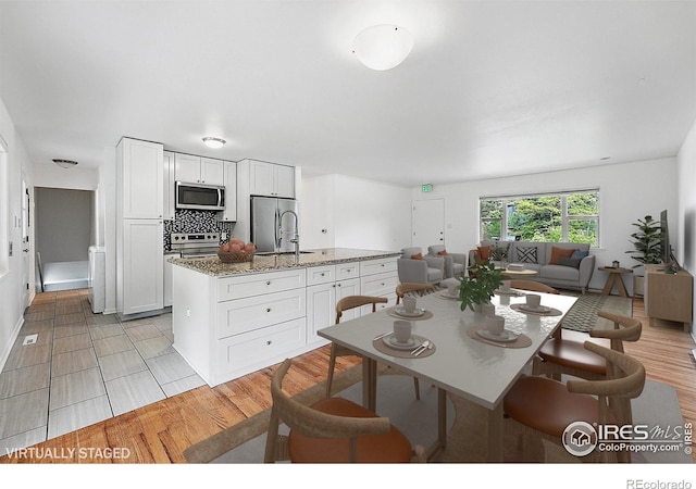 4462 Hamilton Ct, Boulder, CO 80305 - kitchen featuring appliances with stainless steel finishes, a center island with sink, white cabinetry, and open floor plan