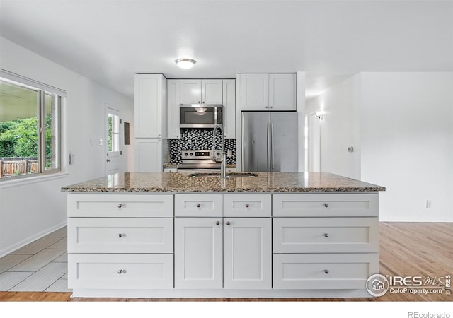4462 Hamilton Ct, Boulder, CO 80305 - kitchen with appliances with stainless steel finishes, stone counters, white cabinetry, a kitchen island with sink, and a sink