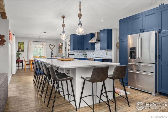 365 Mohawk Dr, Boulder, CO 80303 - kitchen with high end refrigerator, blue cabinets, wall chimney range hood, tasteful backsplash, and a kitchen breakfast bar