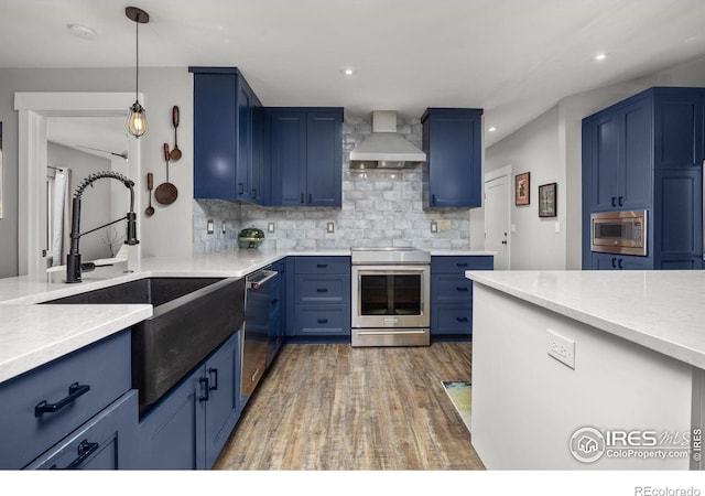 365 Mohawk Dr, Boulder, CO 80303 - kitchen featuring stainless steel appliances, wall chimney exhaust hood, blue cabinetry, a sink, and wood finished floors