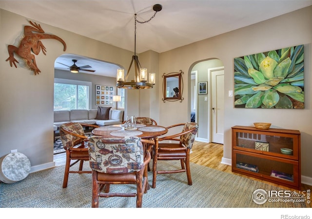 1233 Carolina Ave, Longmont, CO 80501 - dining space featuring arched walkways, ceiling fan, baseboards, a chandelier, and wood finished floors