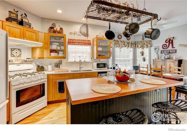 1421 Canal Dr, Windsor, CO 80550 - kitchen featuring white appliances, a sink, under cabinet range hood, wood counters, and recessed lighting