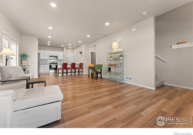 3635 Ronald Reagan Ave, Wellington, CO 80549 - living room featuring stairway, light wood finished floors, recessed lighting, and baseboards