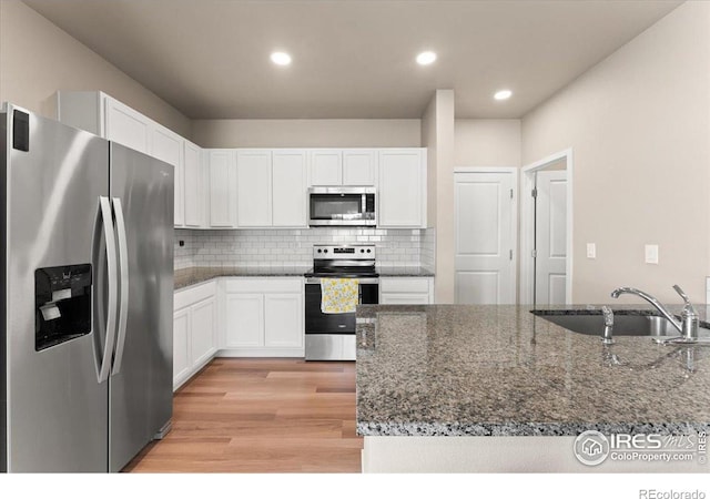 3635 Ronald Reagan Ave, Wellington, CO 80549 - kitchen with stainless steel appliances, light wood finished floors, a sink, white cabinetry, and recessed lighting