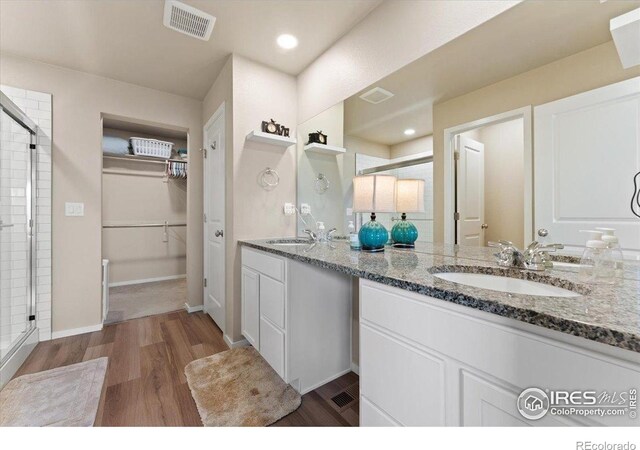 3635 Ronald Reagan Ave, Wellington, CO 80549 - bathroom with a stall shower, wood finished floors, double vanity, a spacious closet, and recessed lighting