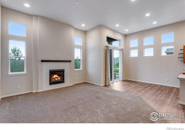 3997 Forest Lake Ct, Loveland, CO 80538 - unfurnished living room featuring carpet flooring, a tiled fireplace, recessed lighting, and baseboards