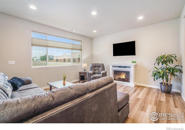 3960 Sweetgum St, Wellington, CO 80549 - living area featuring light wood-style floors, baseboards, recessed lighting, and a lit fireplace