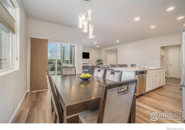 3960 Sweetgum St, Wellington, CO 80549 - kitchen with stainless steel dishwasher, light wood-type flooring, white cabinetry, pendant lighting, and light countertops