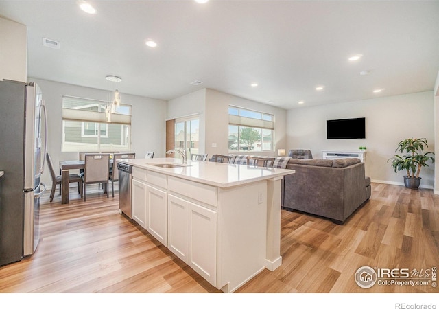 3960 Sweetgum St, Wellington, CO 80549 - kitchen featuring appliances with stainless steel finishes, a sink, white cabinetry, light wood-style floors, and recessed lighting