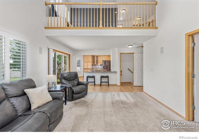 10400 Foxfire St, Firestone, CO 80504 - living area featuring a towering ceiling, light carpet, baseboards, and light wood finished floors