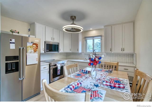 10940 Utica Ct, Westminster, CO 80031 - kitchen featuring appliances with stainless steel finishes, white cabinetry, light countertops, decorative backsplash, and recessed lighting