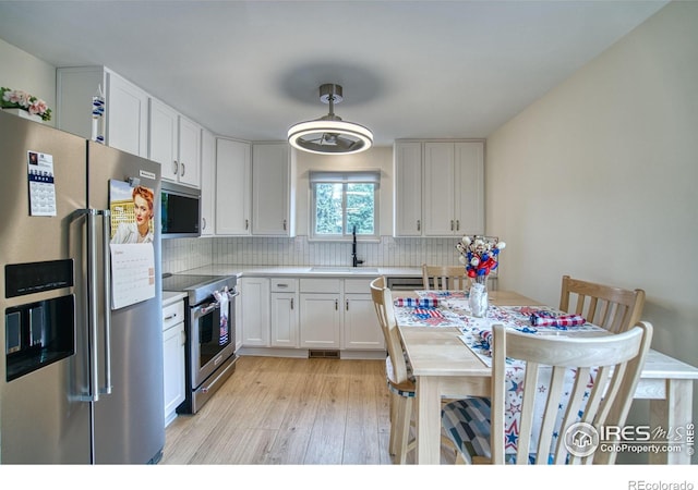 10940 Utica Ct, Westminster, CO 80031 - kitchen with stainless steel appliances, a sink, white cabinetry, and light wood finished floors