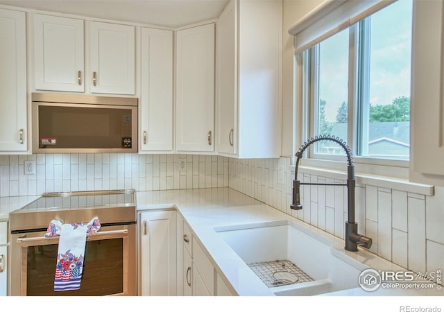 10940 Utica Ct, Westminster, CO 80031 - kitchen with stainless steel appliances, a sink, light countertops, white cabinetry, and backsplash