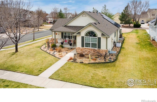 1421 Snipe Ln, Fort Collins, CO 80524 - view of front of home with solar panels, roof with shingles, a front lawn, and stone siding