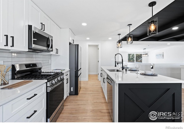 6766 Zenobia Loop, Westminster, CO 80030 - kitchen with appliances with stainless steel finishes, light wood-type flooring, a sink, a kitchen island with sink, and white cabinetry
