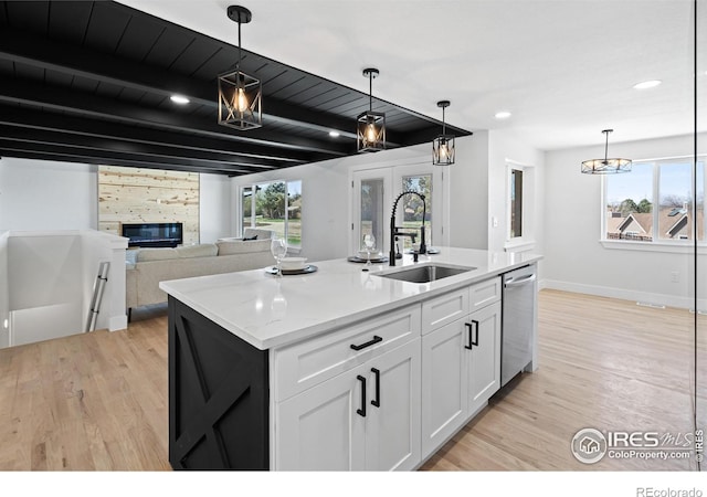 6766 Zenobia Loop, Westminster, CO 80030 - kitchen featuring a sink, stainless steel dishwasher, light wood-style floors, white cabinetry, and beamed ceiling