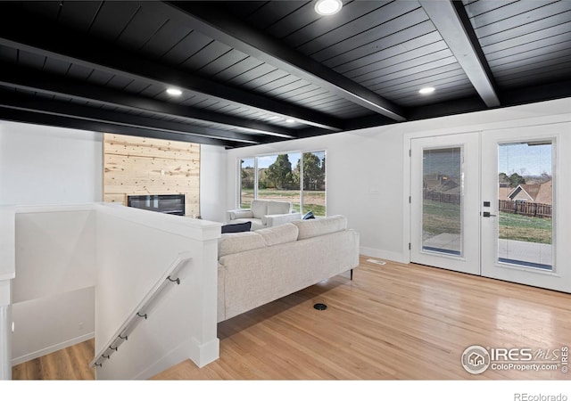 6766 Zenobia Loop, Westminster, CO 80030 - living room featuring light wood-style floors, french doors, wood ceiling with exposed beams, baseboards, and a glass covered fireplace