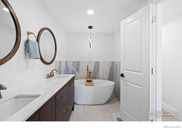 6766 Zenobia Loop, Westminster, CO 80030 - full bathroom featuring a soaking tub, double vanity, tile walls, recessed lighting, and wainscoting