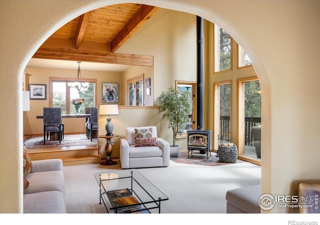 187 Rocky Knob Ln, Nederland, CO 80466 - carpeted living area featuring a wood stove, wooden ceiling with exposed beams, a chandelier, and arched walkways