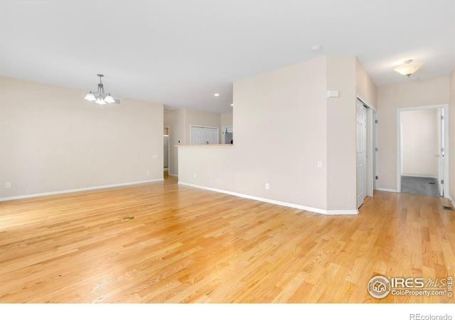 3180 Springfield Dr, Loveland, CO 80538 - unfurnished living room featuring a chandelier, light wood finished floors, and baseboards