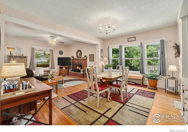 6009 W 28th St W, Greeley, CO 80634 - dining space with light wood-type flooring, a fireplace, healthy amount of natural light, a textured ceiling, and a chandelier
