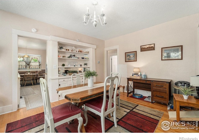 6009 W 28th St W, Greeley, CO 80634 - dining area with light wood finished floors, a chandelier, and a textured ceiling