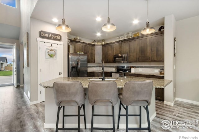 6757 Sage Meadows Dr, Wellington, CO 80549 - kitchen with appliances with stainless steel finishes, a sink, dark brown cabinets, light wood-style flooring, and recessed lighting