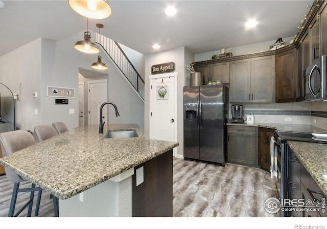 6757 Sage Meadows Dr, Wellington, CO 80549 - kitchen with stainless steel appliances, a sink, a kitchen bar, and dark brown cabinetry