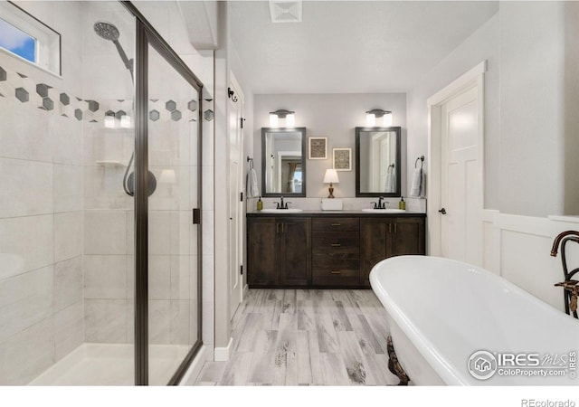 6757 Sage Meadows Dr, Wellington, CO 80549 - full bath featuring a stall shower, a freestanding tub, double vanity, wood finished floors, and wainscoting