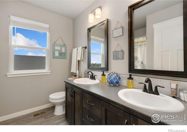 6757 Sage Meadows Dr, Wellington, CO 80549 - bathroom featuring double vanity, wood finished floors, toilet, and baseboards