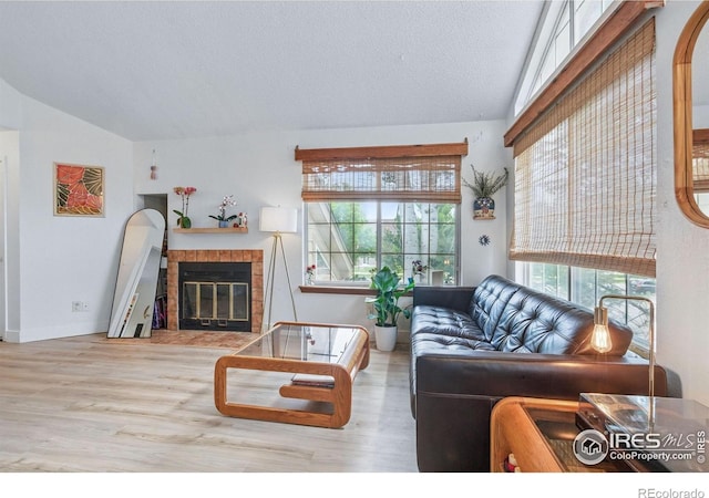 6076 Gunbarrel Ave Unit F, Boulder, CO 80301 - living room with lofted ceiling, wood finished floors, a tiled fireplace, baseboards, and a textured ceiling