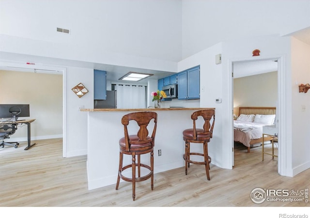 6076 Gunbarrel Ave Unit F, Boulder, CO 80301 - kitchen featuring blue cabinetry, stainless steel appliances, light wood-style floors, and a kitchen breakfast bar